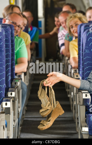 Deutschland, München, Bayern, Hände halten high-Heel-Sandalen in Economy-Class-Verkehrsflugzeug Stockfoto