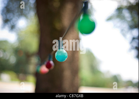 Eine Zeichenkette von bunten Glas lichter Hände zwischen Bäumen. Stockfoto