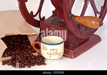 Nahaufnahme einer altmodischen Kaffeemühle mit Bohnen und einer erfrischenden Tasse für frischen Kaffee. Stockfoto