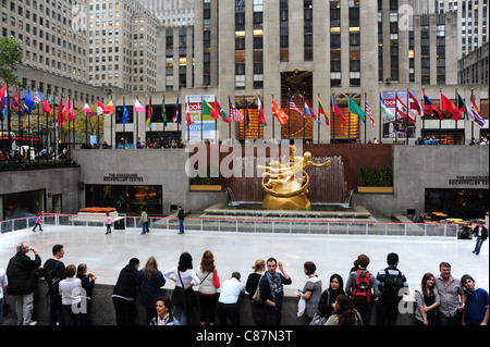 Leuteaufpassen Skater, in Richtung gold Prometheus Skulptur, Fahnen, "30 Rock", versunkene Eisbahn, Rockefeller Center, New York, USA Stockfoto