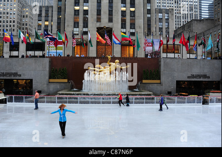 Weiblichen Schlittschuhläufer drehende vordere gold Prometheus Skulptur, Fahnen, "30 Rock", Rockefeller Center Ice Rink, New York, USA Stockfoto