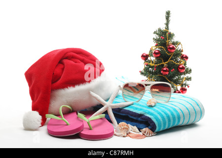 Weihnachtsmann-Mütze und Weihnachtsbaum mit Strand-Accessoires auf weißem Hintergrund. Stockfoto