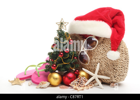 Weihnachtsmann-Mütze und Weihnachtsbaum mit Strand-Accessoires auf weißem Hintergrund. Stockfoto