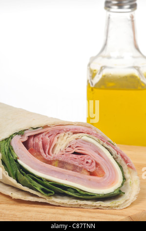 Italienische Wurstwaren wrap Sandwich mit Salat, Käse und Tomaten und eine Flasche Olivenöl auf weißem Hintergrund. USA Stockfoto