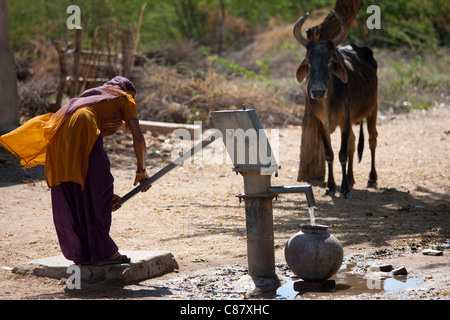 Indische Frau Pumpen von Wasser aus einem Brunnen im Jawali Dorf in Rajasthan, Nordindien Stockfoto