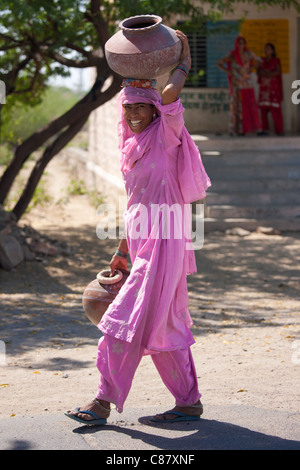 Indische Frau in Sari tragen Wasser Töpfe zu füllen aus Brunnen im Jawali Dorf in Rajasthan, Nordindien Stockfoto