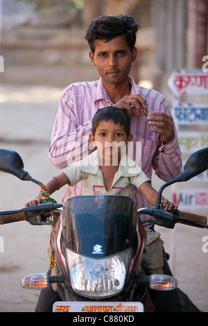 Indischer Mann mit Kind auf einem Motorrad in Narlai Dorf in Rajasthan, Nordindien Stockfoto