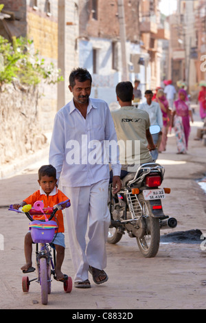 Indischer Mann mit Kind auf dem Dreirad in das Dorf Narlai in Rajasthan, Nordindien Stockfoto