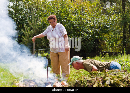 Älteres Paar versucht, ein Lagerfeuer im Garten machen. Stockfoto