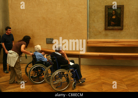 Behinderte Besucher im Rollstuhl geniessen das Porträt der Mona Lisa von Leonardo da Vinci im Louvre in Paris, Frankreich. Stockfoto