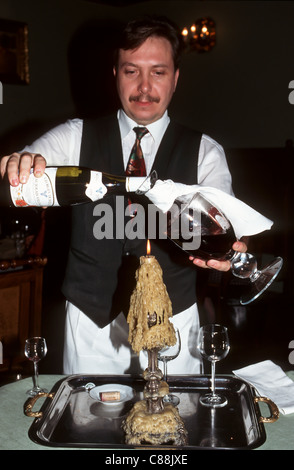 Krakau, Polen. Kellner Umfüllen von einer Flasche Beaujolais in ein Glas-Dekanter mit einer Kerze in eine Kerze mit Wachs beträufelt. Stockfoto