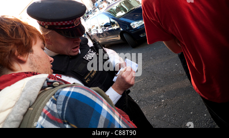 Occupy London Stock Exchange Demonstration 15/10/2011. Die städtische Polizei kontrolliert den Zugang zur Demonstration an der St. Paul's Cathedral. Ein Polizist nimmt die persönlichen Daten eines jungen Mannes mit, bevor er sich der Hauptdemonstration auf den Stufen von St. Paul's, London England UK, anschließen kann. KATHY DEWITT Stockfoto