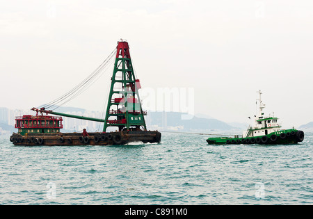 Abzulehnen Sie, Lastkahn mit Kran unter Schlepptau durch Schlepper in Kowloon Bay Victoria Harbour Hong Kong China Asien Recycling Stockfoto