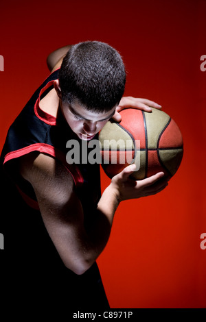Basketball-Spieler mit Ball auf rotem Hintergrund isoliert Stockfoto