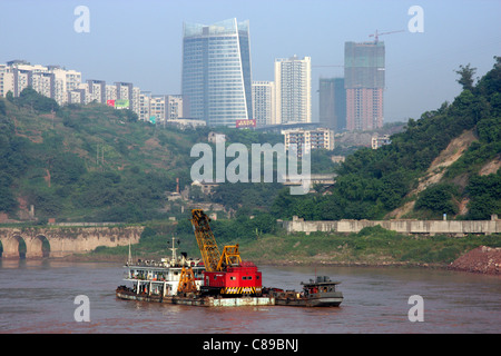 Skyline der Stadt und eine große Muschel Baggern am Jangtse-Fluss in Chongqing, China Stockfoto