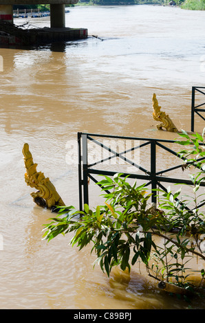 Zwei Drachen (Naga) Skulpturen im Sonnenschein, die teilweise unter Wasser durch Hochwasser des Flusses Ping in der Nähe von Chiang Mai Thailand Stockfoto