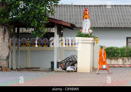 Buddhistischer Mönch mit großen Metall-Eimer geht über Hof bei kleinen Thai Tempel namens Wat Tam Nag in Nordthailand. Stockfoto