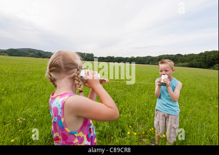 Deutschland, Nordrhein-Westfalen, Hennef, jungen und Mädchen auf Wiese spielen mit Zinn können telefonisch Stockfoto