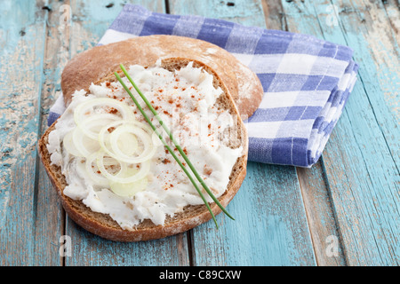 Nahaufnahme der Brotscheibe mit Ausbreitung, Zwiebel und Paprika auf aufgegebenes Serviette Stockfoto