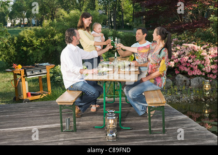 Deutschland, Bayern, Freunde genießen Sie Speisen und Getränke mit Grill im Vordergrund Stockfoto