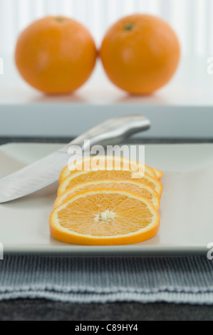 Ganze Orange mit Scheiben auf Teller, Nahaufnahme Stockfoto