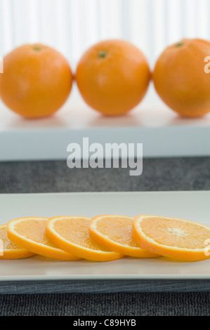 Ganze Orange mit Scheiben auf Teller, Nahaufnahme Stockfoto