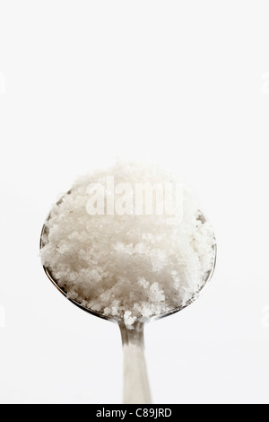 Löffel voll von Fleur de Sel vor weißem Hintergrund, in der Nähe Stockfoto