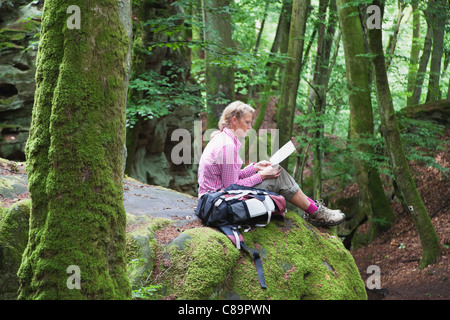 Deutschland Rheinland-Pfalz Süd Eifel Natur Park Frau Wanderer sitzen auf Buntsandstein Felsformationen am Baum Buchenwald Stockfoto