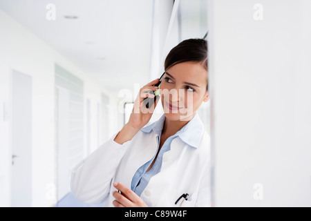 Deutschland, Bayern, Diessen am Ammersee, junger Arzt Gespräch am Mobiltelefon und schiefen, Lächeln Stockfoto