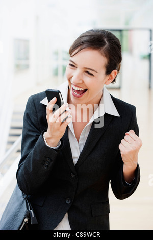 Deutschland, Bayern, Diessen am Ammersee, junge Geschäftsfrau halten Handys, lachen Stockfoto