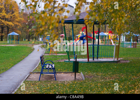 Eine leere Park und einen Spielplatz für Kinder auf einem nassen und regnerischen Herbsttag Stockfoto
