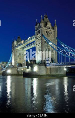 Tower Bridge vom Südufer der Themse, London UK, bei Nacht, beleuchtet, mit blauem Himmel und Reflexionen im Fluss Stockfoto