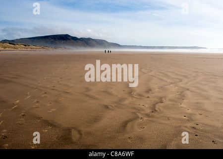 Fernen Figuren zu Fuß auf einem verlassenen Rhossili Bucht-Strand auf der Halbinsel Gower, South Wales. Stockfoto