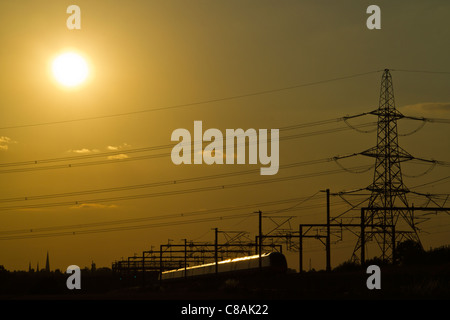 Jungfrau-Züge Pendolino-Zug fängt die Sonne glitzern der späten Abendsonne, Huddlesford, Lichfield, Staffordshire, England. Stockfoto