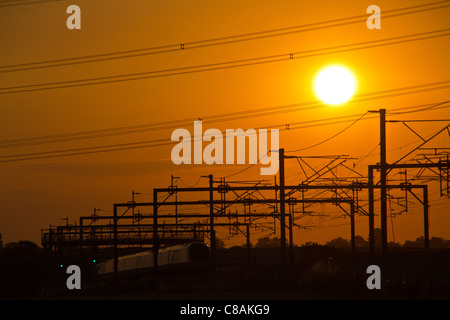 Jungfrau-Züge Pendolino-Zug fängt die Sonne glitzern der späten Abendsonne, Huddlesford, Lichfield, Staffordshire, England. Stockfoto