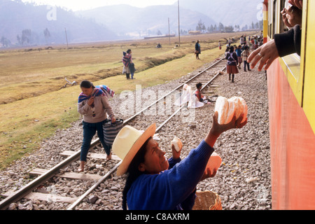 Machu Pichu Eisenbahn, Peru. Frau in traditioneller Kleidung, Brot für die Reisenden im Zug verkauft. Stockfoto