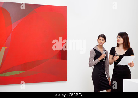 Junge Frauen betrachten Wandmalerei in Kunstgalerie Stockfoto