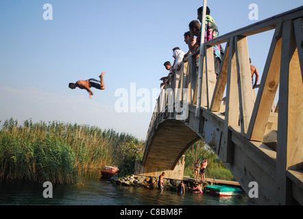 AKYAKA, TÜRKEI. Ein Mann von einer hölzernen Brücke in den Fluss Azmak Tauchen. 2011. Stockfoto