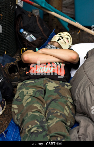 Besetzen Sie Wall Street Demonstranten tragen Guy Fawkes Maske schläft im Zuccotti Park nach einer angespannten Nacht Reinigung um Räumung zu vermeiden. Stockfoto