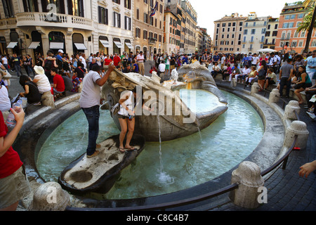 Die Touristen rund um den Barcaccia Brunnen auf der Piazza di Spagna in der Nähe der spanischen Treppe in Rom, Italien. Stockfoto