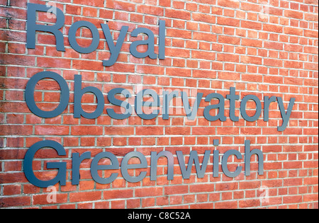 Eine Metall Buchstaben Zeichen auf einer roten Backsteinmauer kündigt die Lage des Royal Observatory in Greenwich, London. Stockfoto