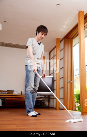 Junger Mann fegen Boden mit Boden-mop Stockfoto