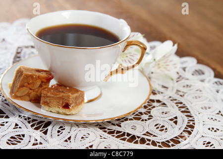 Kekse und Kaffee mit Blume auf hölzernen Hintergrund mit weißer Spitze Serviette verziert Stockfoto