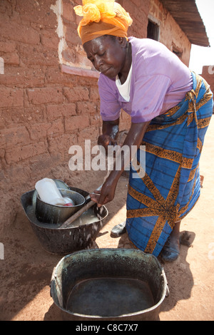 Eine Frau wäscht ihre Hände vor ihrem Haus in Mongu, Sambia, Südafrika. Stockfoto