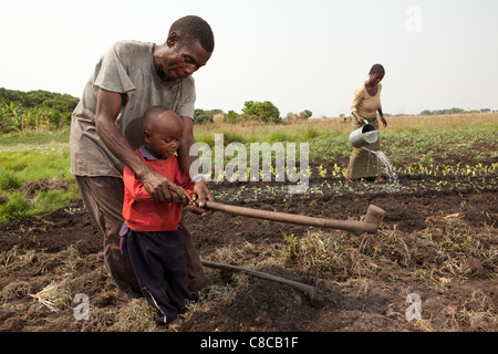 Ein Bauer lehrt seinen jungen Sohn, in Mongu, Sambia, Südafrika zu hacken. Stockfoto