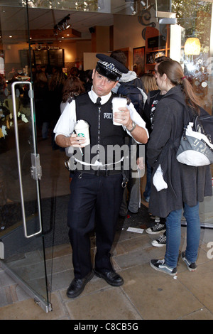 Ein Polizist kauft Kaffee von Starbucks in der Nähe von St Pauls Cathedral während der Londoner Börse besetzen Protest. Stockfoto