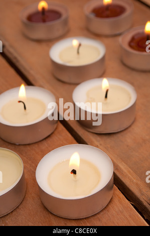 Viele brennende Kerzen auf alter Holztisch Stockfoto