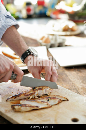 Mann slicing Huhn auf Schneidebrett Stockfoto