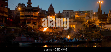 Touristen sehen Hindu Einäscherung auf Scheiterhaufen am Manikarnika Ghat, Fluss Ganges, in der Heiligen Stadt Varanasi, Benares, Indien Stockfoto