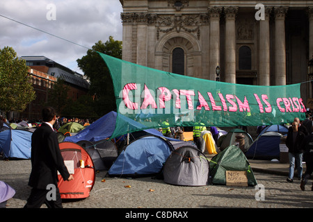 Ein Geschäftsmann, der Blick auf eine antikapitalistische Banner am Protest vor dem St. Pauls Cathedral in London Stockfoto